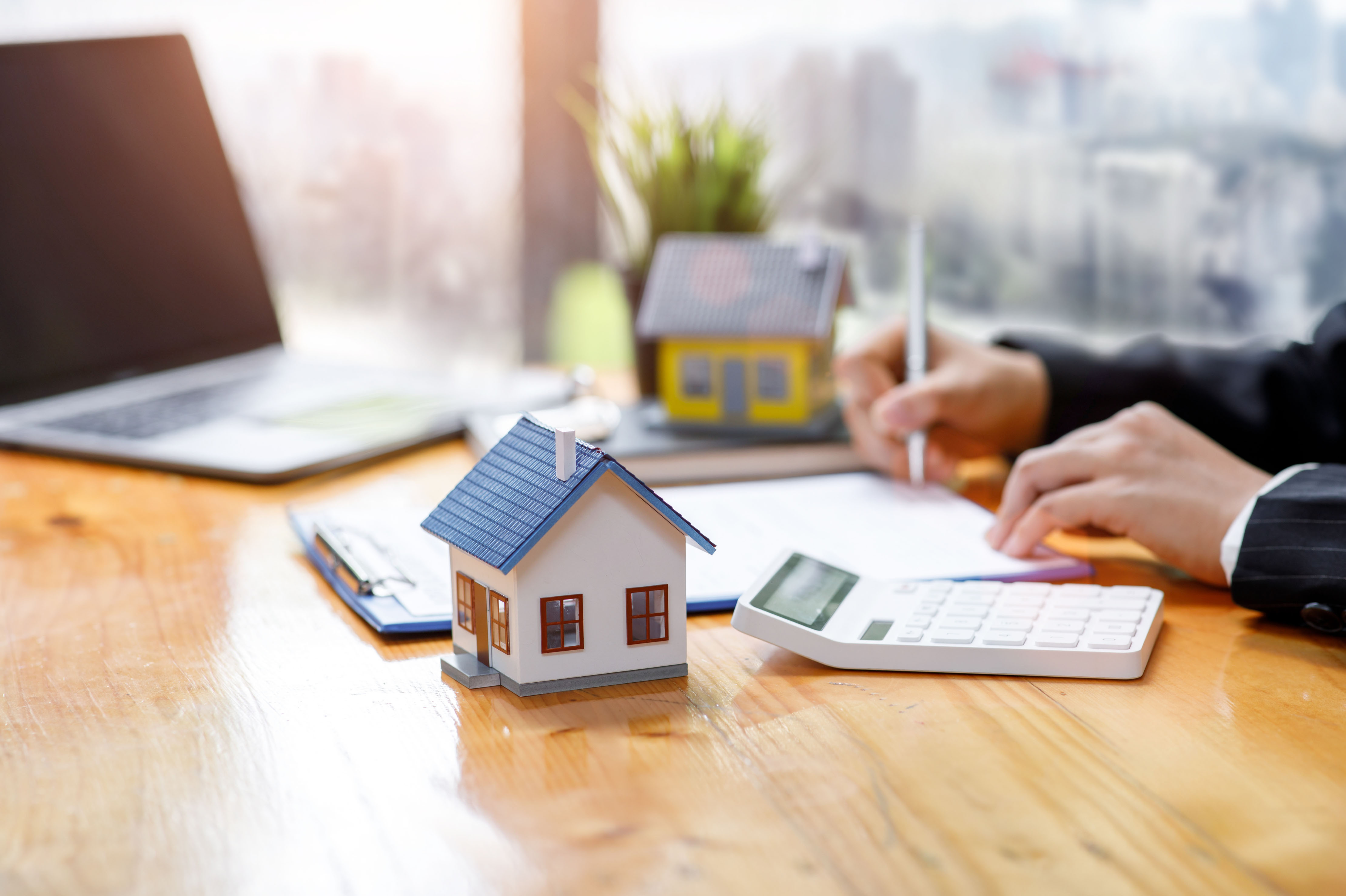 A house model placed on top of financial documents and charts, symbolising property investment and financial planning