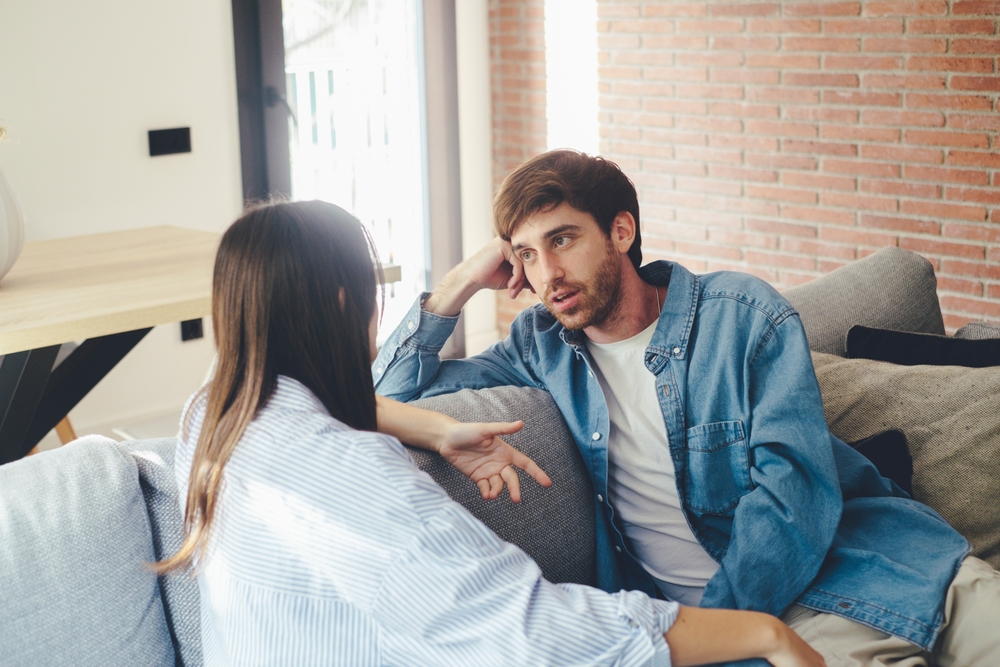 A couple sitting on a sofa talking seriously