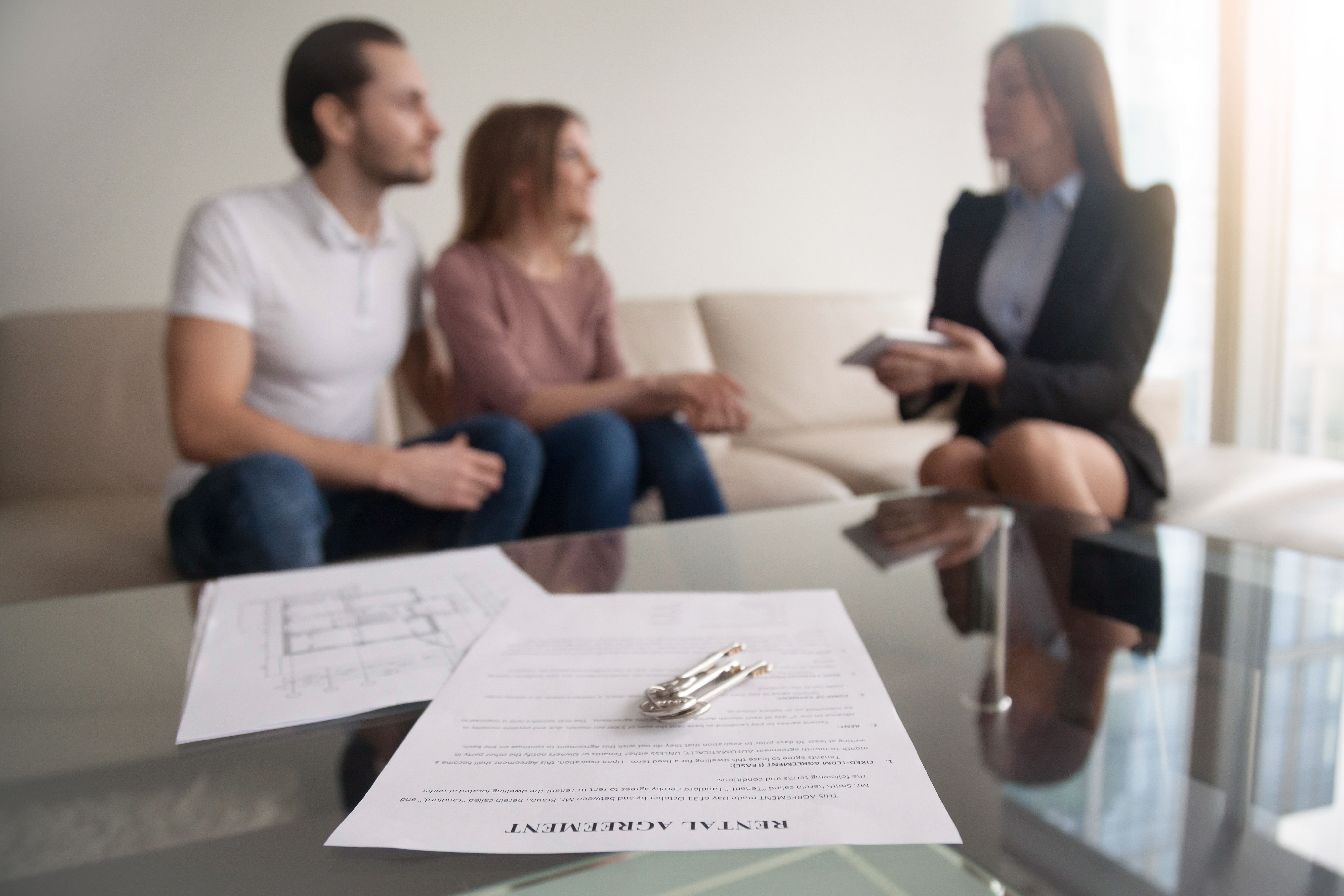 Two people renting a home from a landlord with their rental agreement in front of them