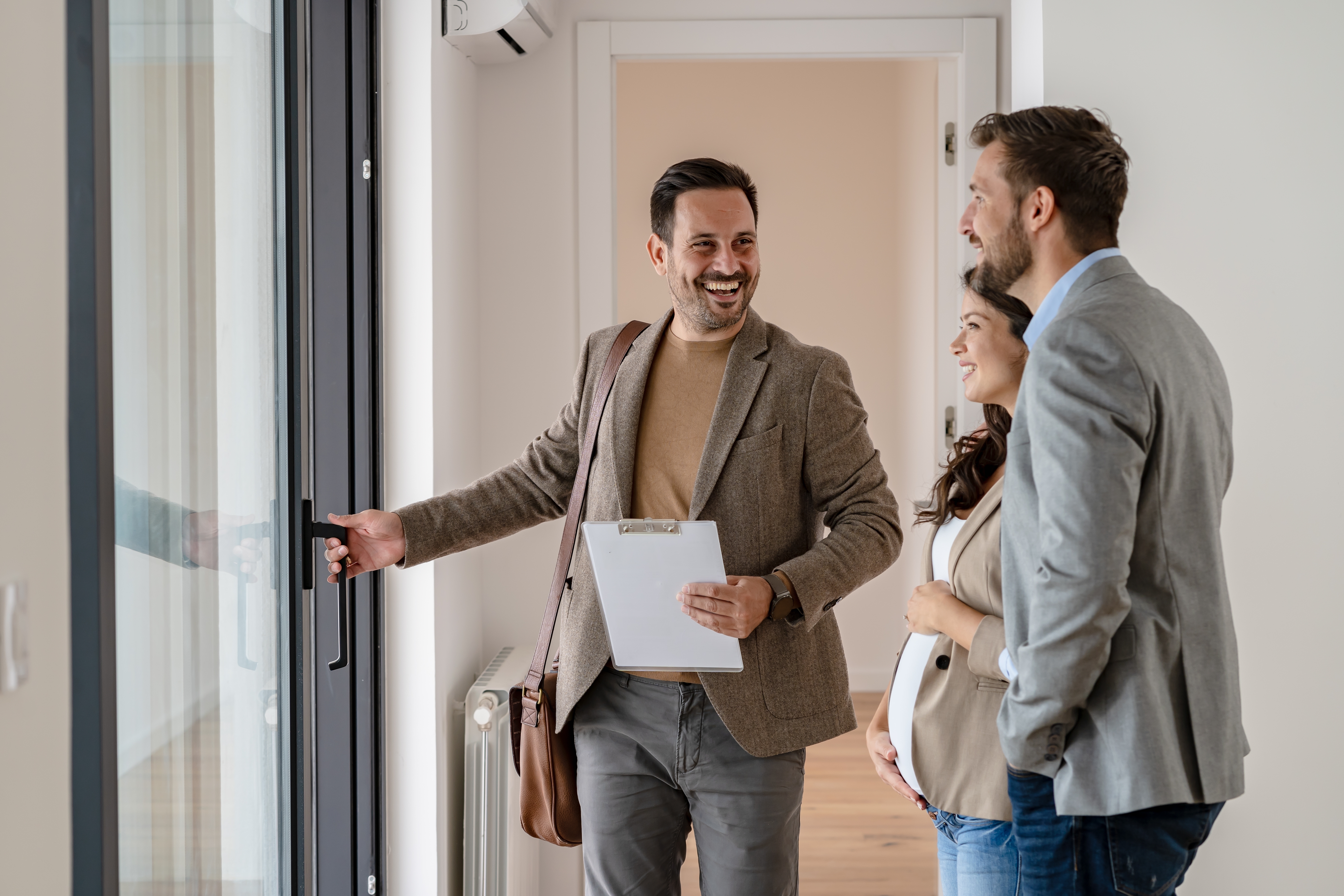 Young couple viewing a house with an estate agent with checklist